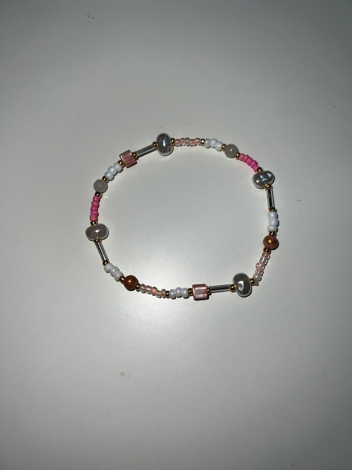 Armband aus weißen und pinkfarbenen Rocailles, Perlen und goldenen Zwischenperlen