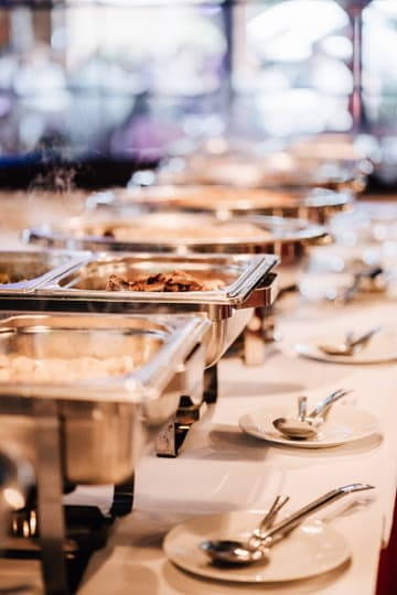 Warmes Buffet mit Chafing Dishes und Besteck auf Tellern
