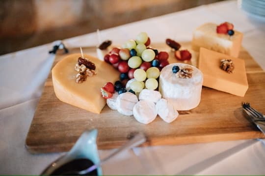 Käseplatte auf Holzbrett mit Hart- und Weichkäse, Trauben, Heidelbeeren, Walnüssen und Datteln