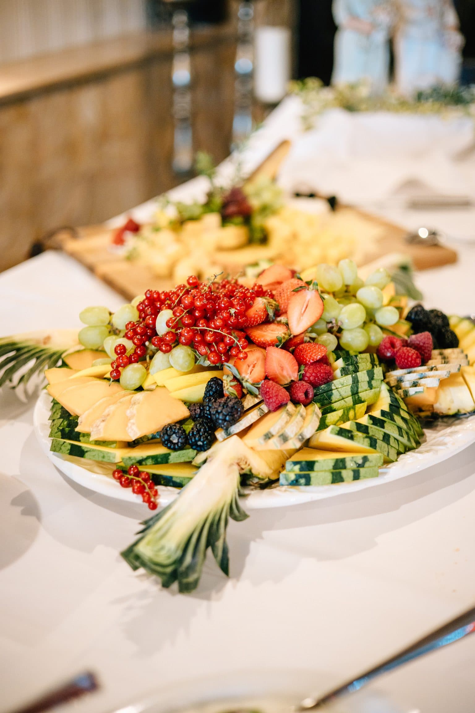 Festliche Obstplatte mit Melone, Ananas, Trauben, Erdbeeren, Himbeeren und Johannisbeeren