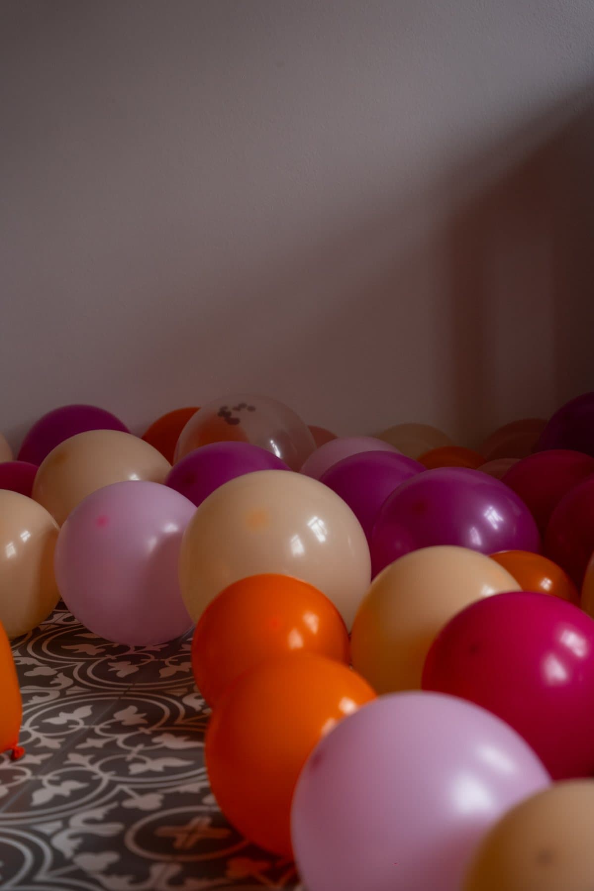 Pinke, orange und cremefarbene Luftballons auf einem gemusterten Fliesenboden