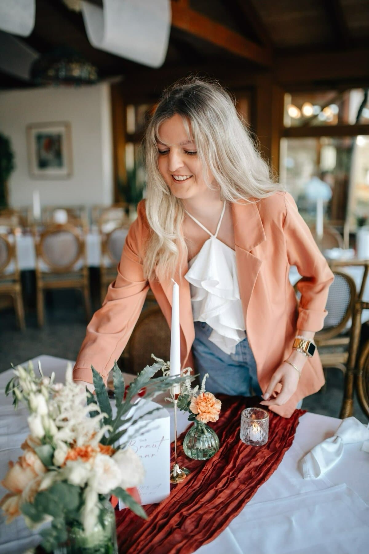 Marie Liebisch beim Dekorieren einer Tafel mit Blumen, Kerze und rostrotem Tischläufer