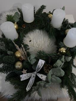 Adventskranz mit weißen Kerzen, goldenen Kugeln, Eukalyptus und weißer Schleife mit Sternen