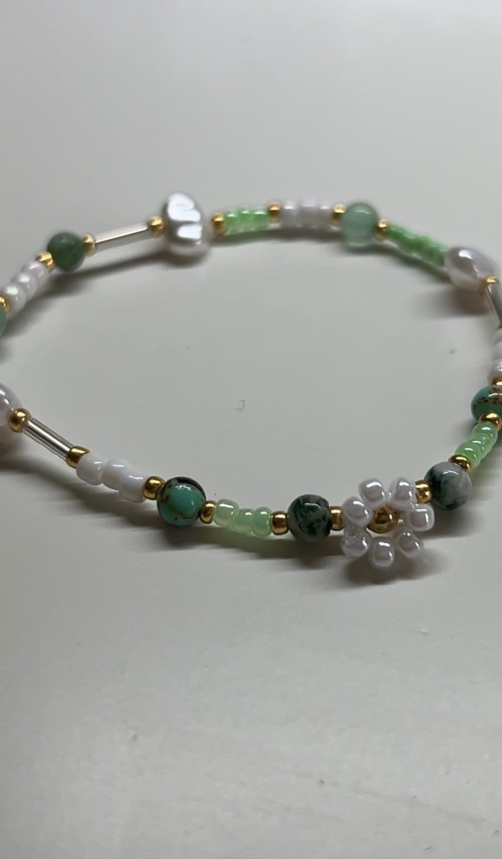 Handgemachtes Armband aus grünen Steinperlen, Rocailles, Süßwasserperlen und einem weißen Perlenblümchen